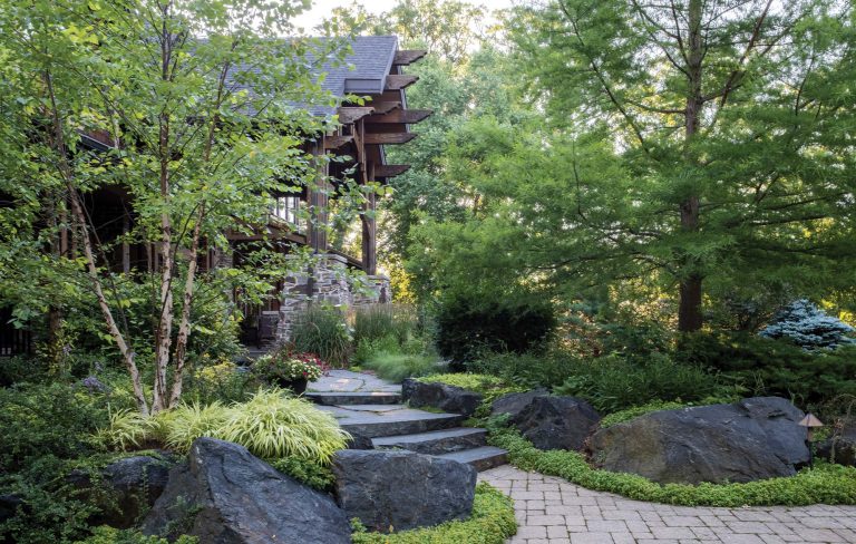 Natural granite steps winding through a lush garden entrance to a luxury home — Kane Brothers landscape design
